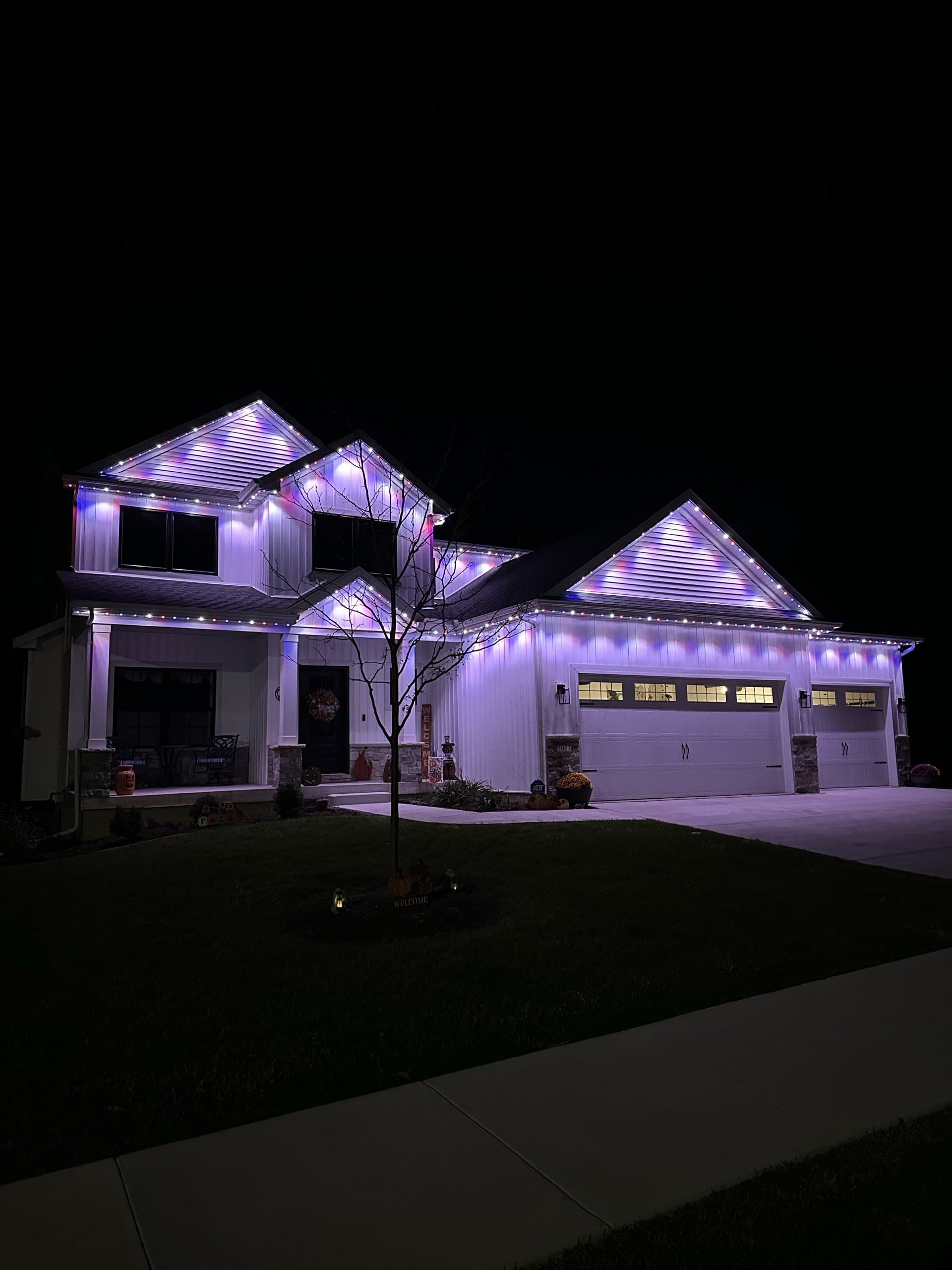 Modern farmhouse with cool-white and purple permanent lighting at dusk