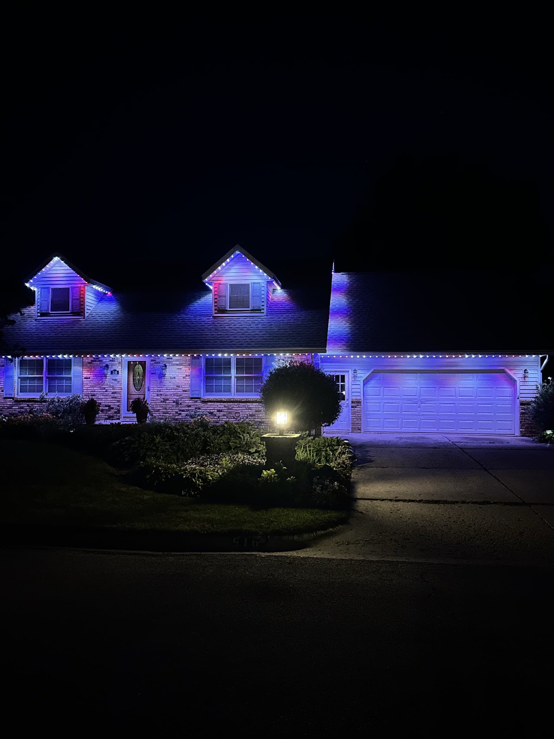 Cape Cod home lit in patriotic red, white, and blue