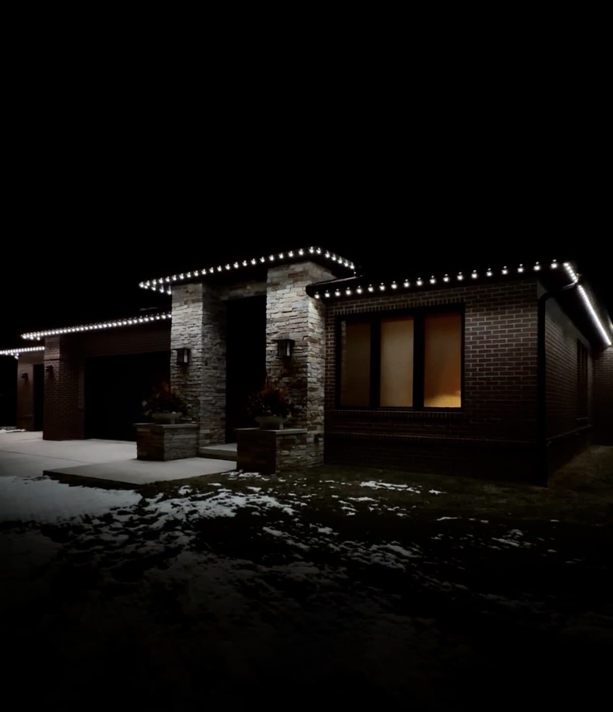 Brick home on a winter night with warm-white permanent lighting